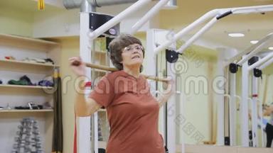 老年妇女用棍子转动，在健身房做理疗。 健康体操。 活跃的老年人。